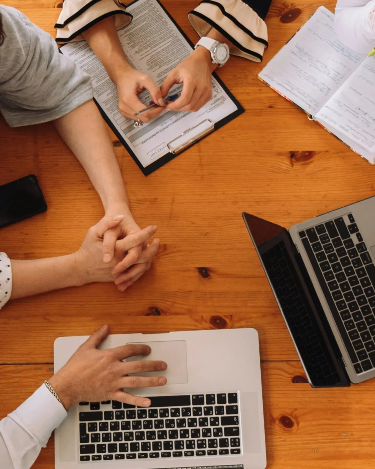 Team around a table with laptops, a contract and handwritten notes